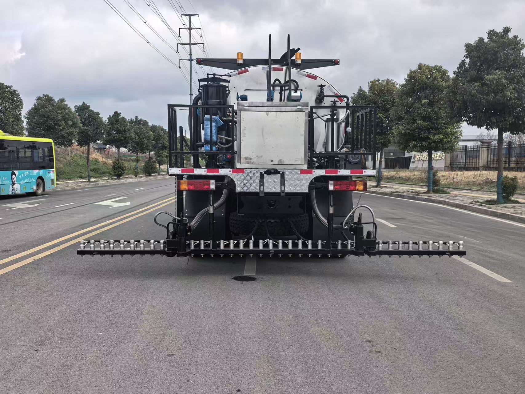 Rear view of an asphalt distributor truck with spray bar and binder piping